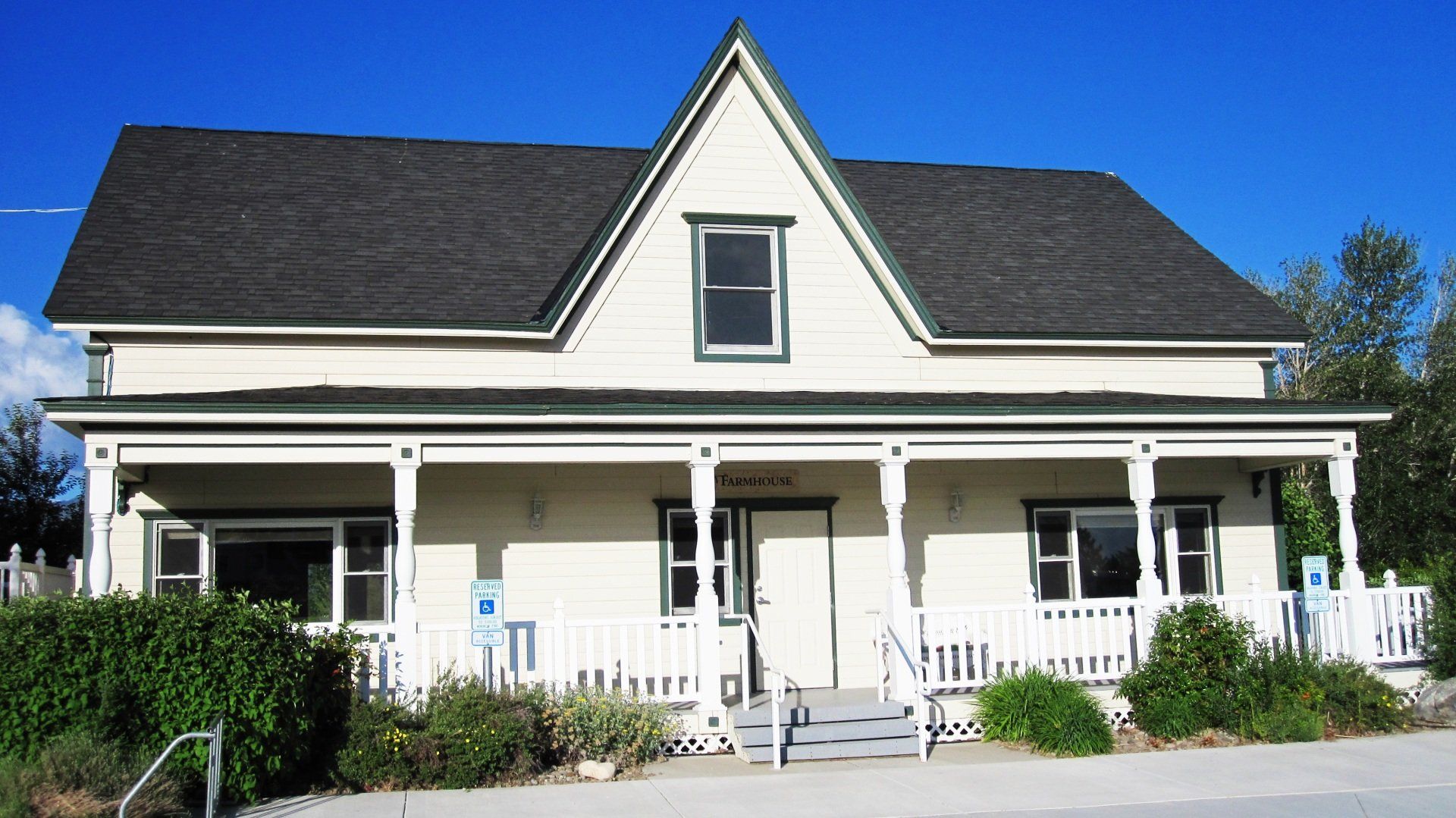 A white house with a black roof and a porch