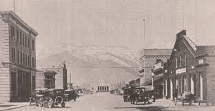 A black and white photo of a city street with cars parked on the side of the road.