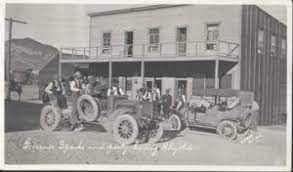 A group of old cars are parked in front of a building.