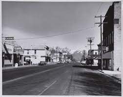 A black and white photo of a city street with mountains in the background.