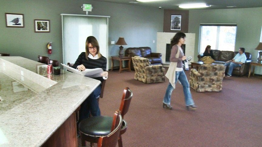 A woman is sitting at a counter reading a magazine