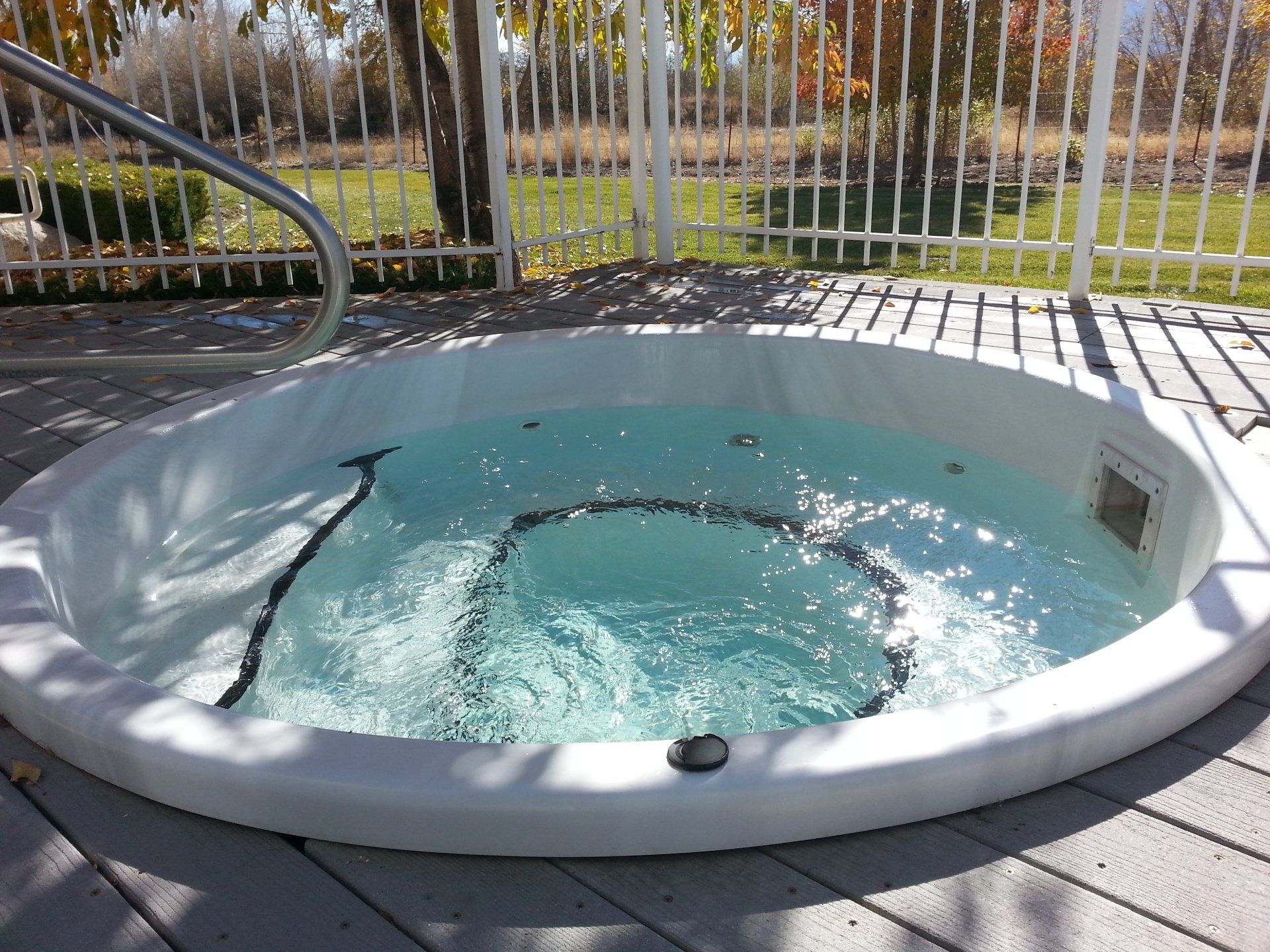 A hot tub is sitting on a deck next to a fence