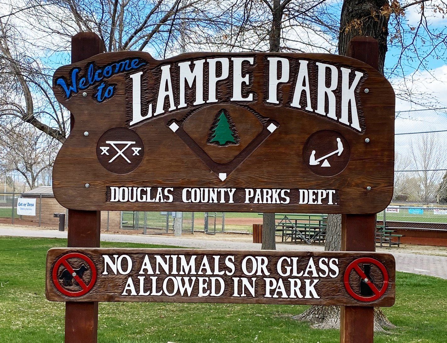 A wooden sign for lampe park says that no animals or glass are allowed in the park.