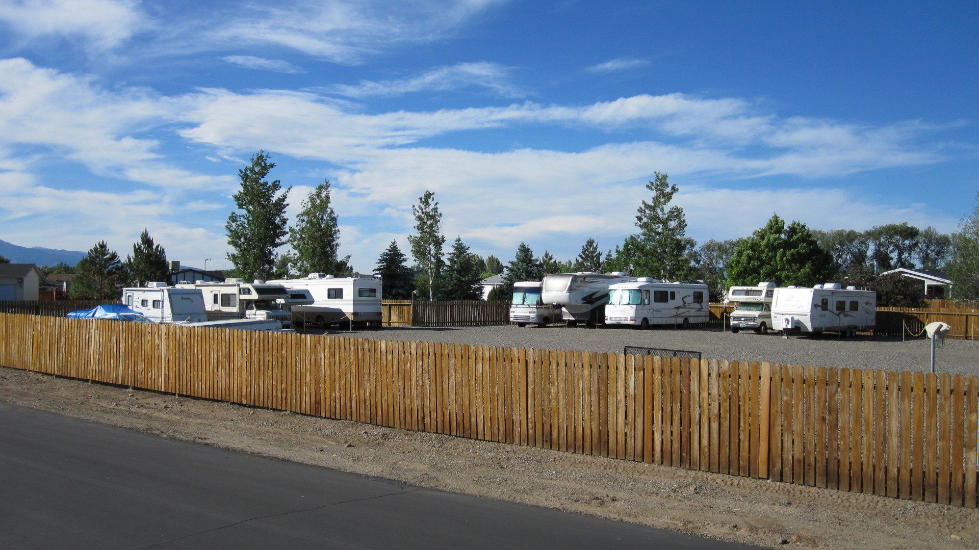 A row of rvs parked behind a wooden fence