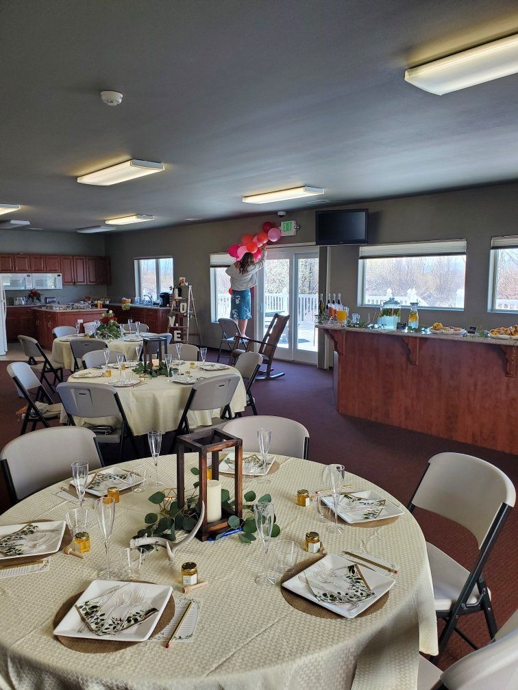 A large room with tables and chairs set up for a wedding reception.