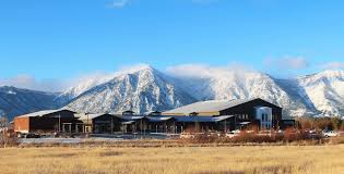 A large building in the middle of a field with mountains in the background.