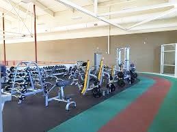 A gym filled with lots of exercise equipment and dumbbells.