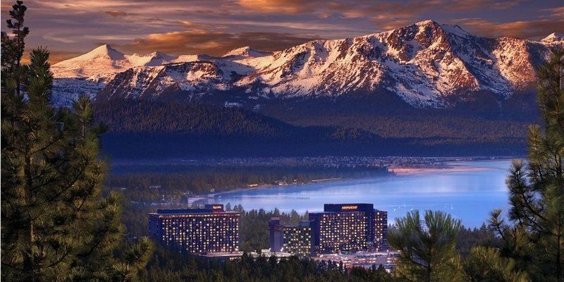 A lake with mountains in the background and a city in the foreground