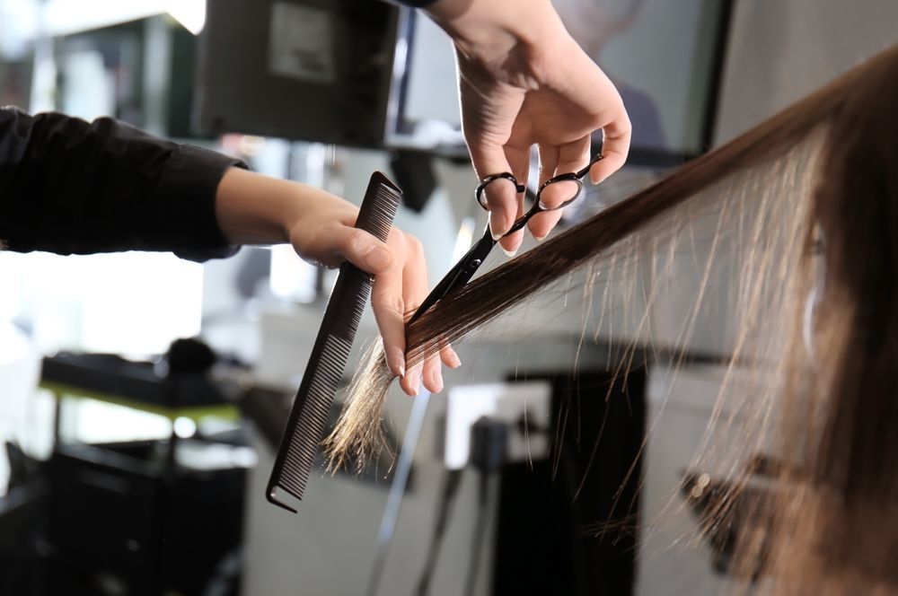 Hairdresser Cutting a Client's Hair With Scissors and a Comb in a Salon Setting — Amore 'D' Hair Studio in Mudjimba, QLD