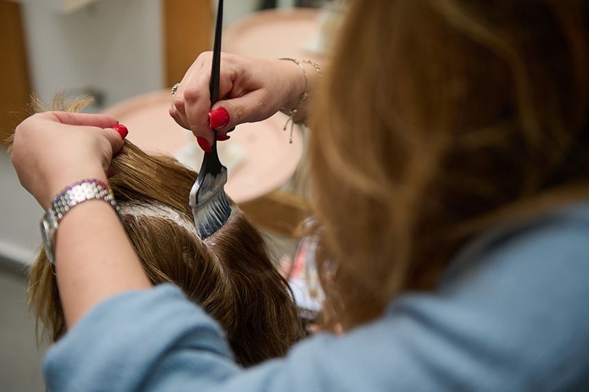 A Woman is Getting Her Hair Dyed by a Hairdresser in a Salon — Amore 'D' Hair Studio In Mudjimba, QLD
