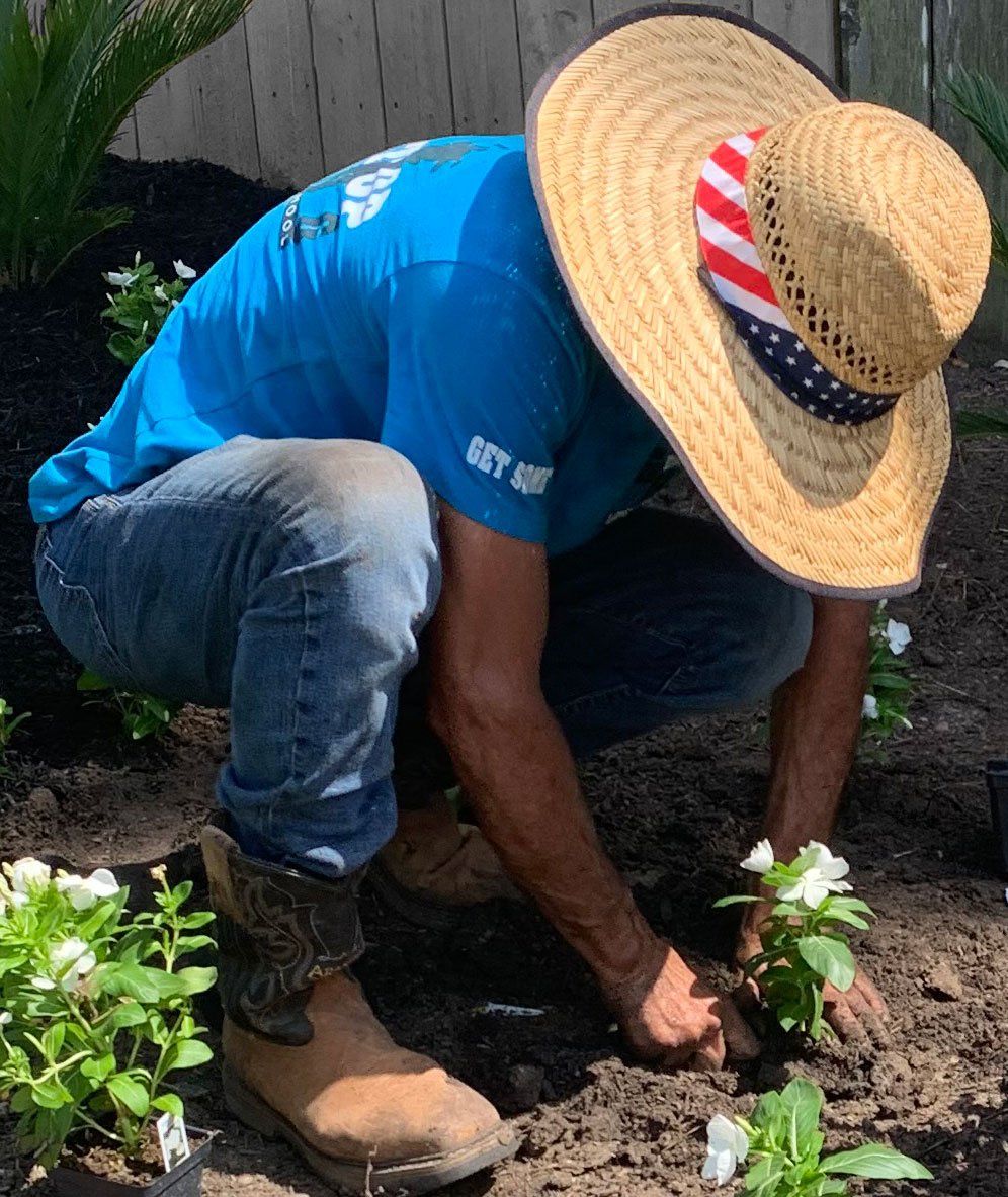 A man wearing a straw hat is working in a garden