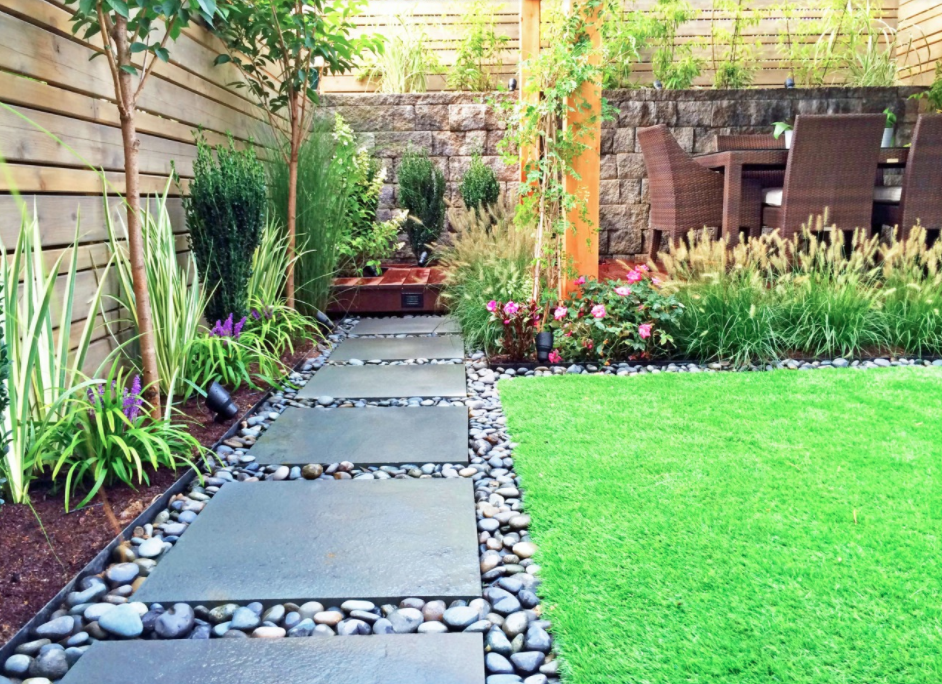 A garden with a stone walkway leading to a lawn.