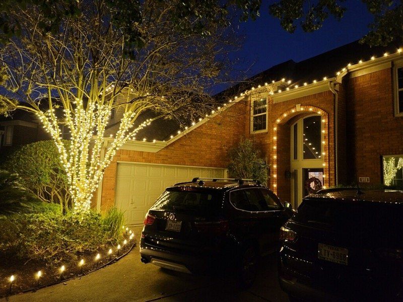A car is parked in front of a house decorated with christmas lights.