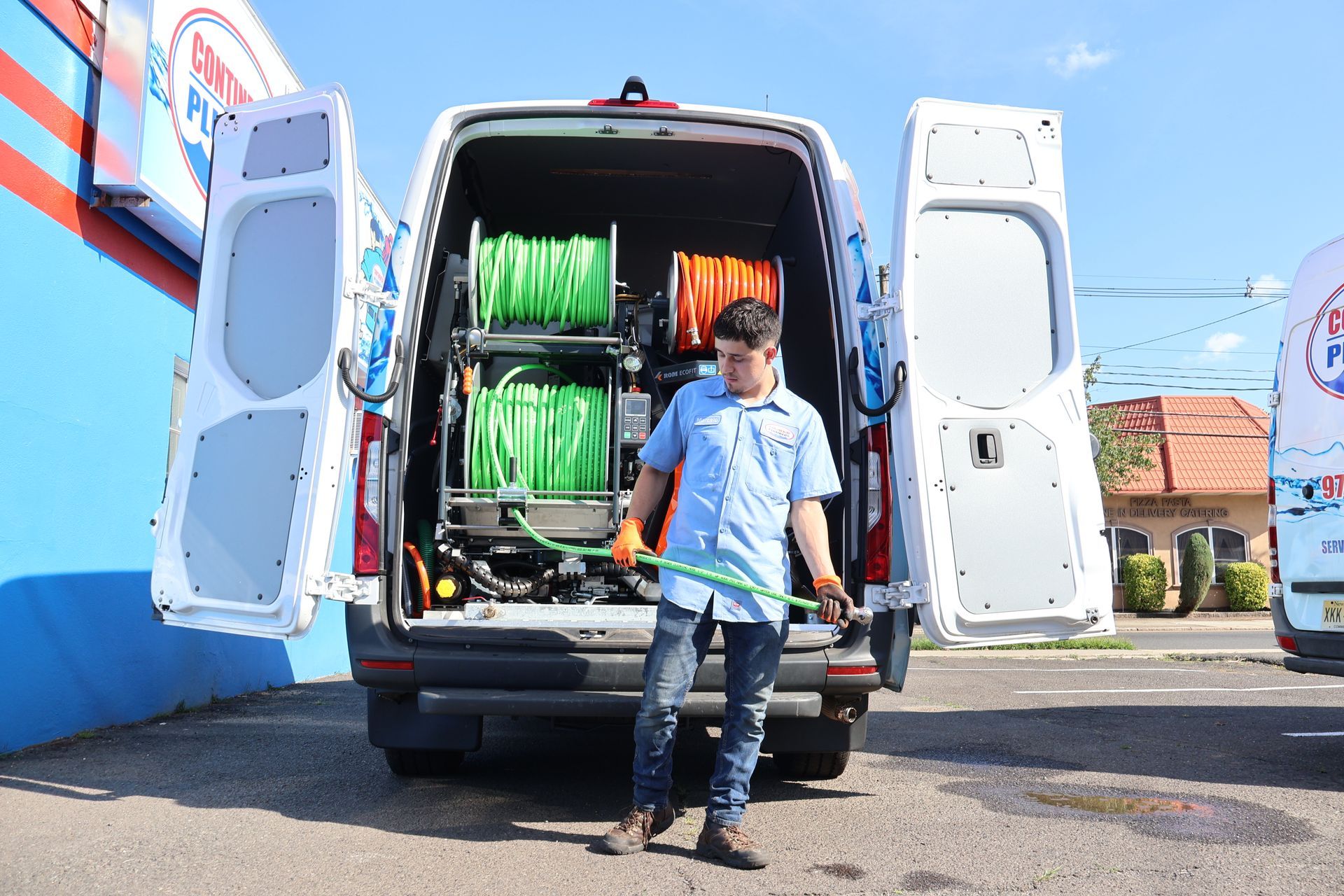 A man is standing in front of a van with the doors open.