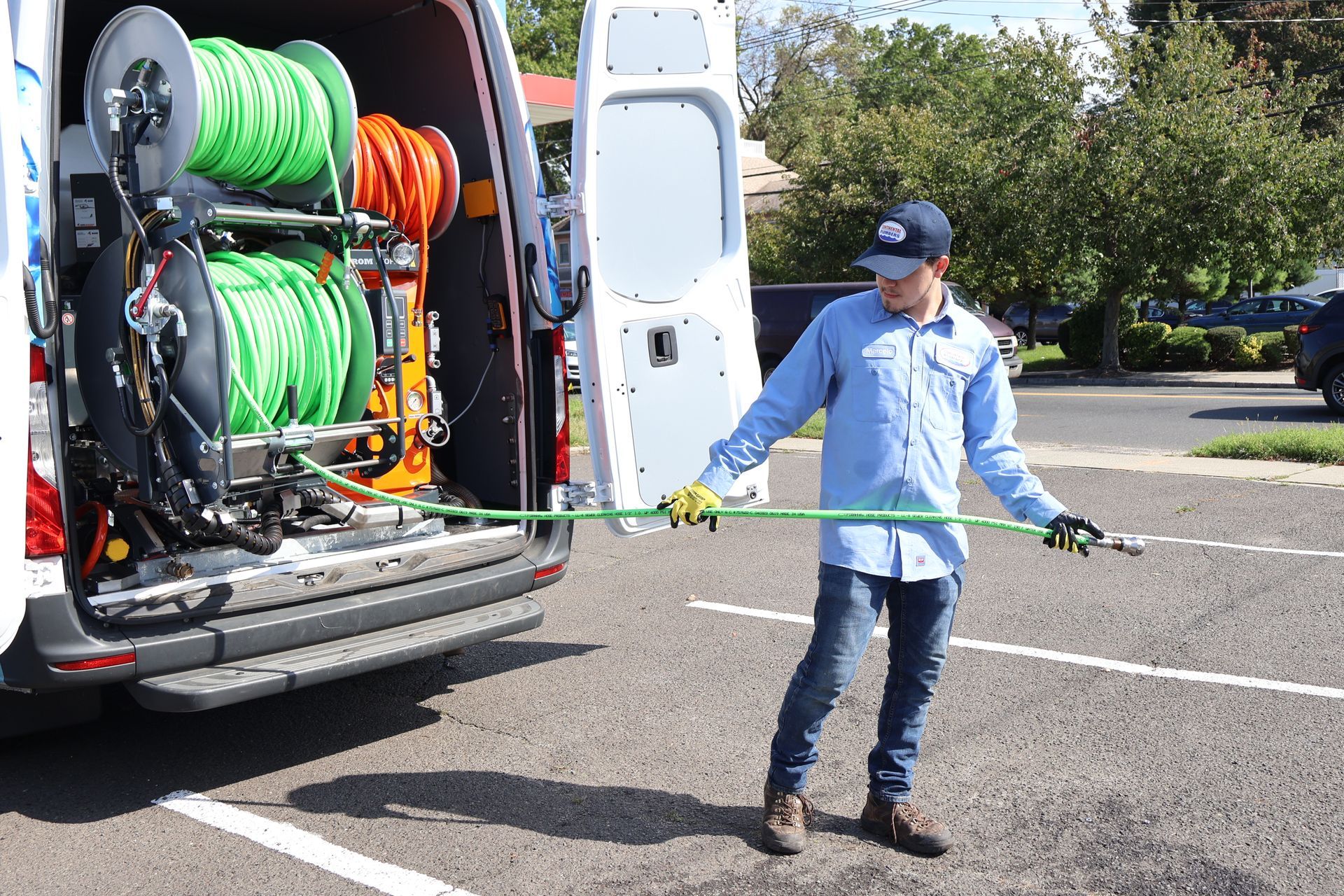 A man is holding a hose in front of a van.