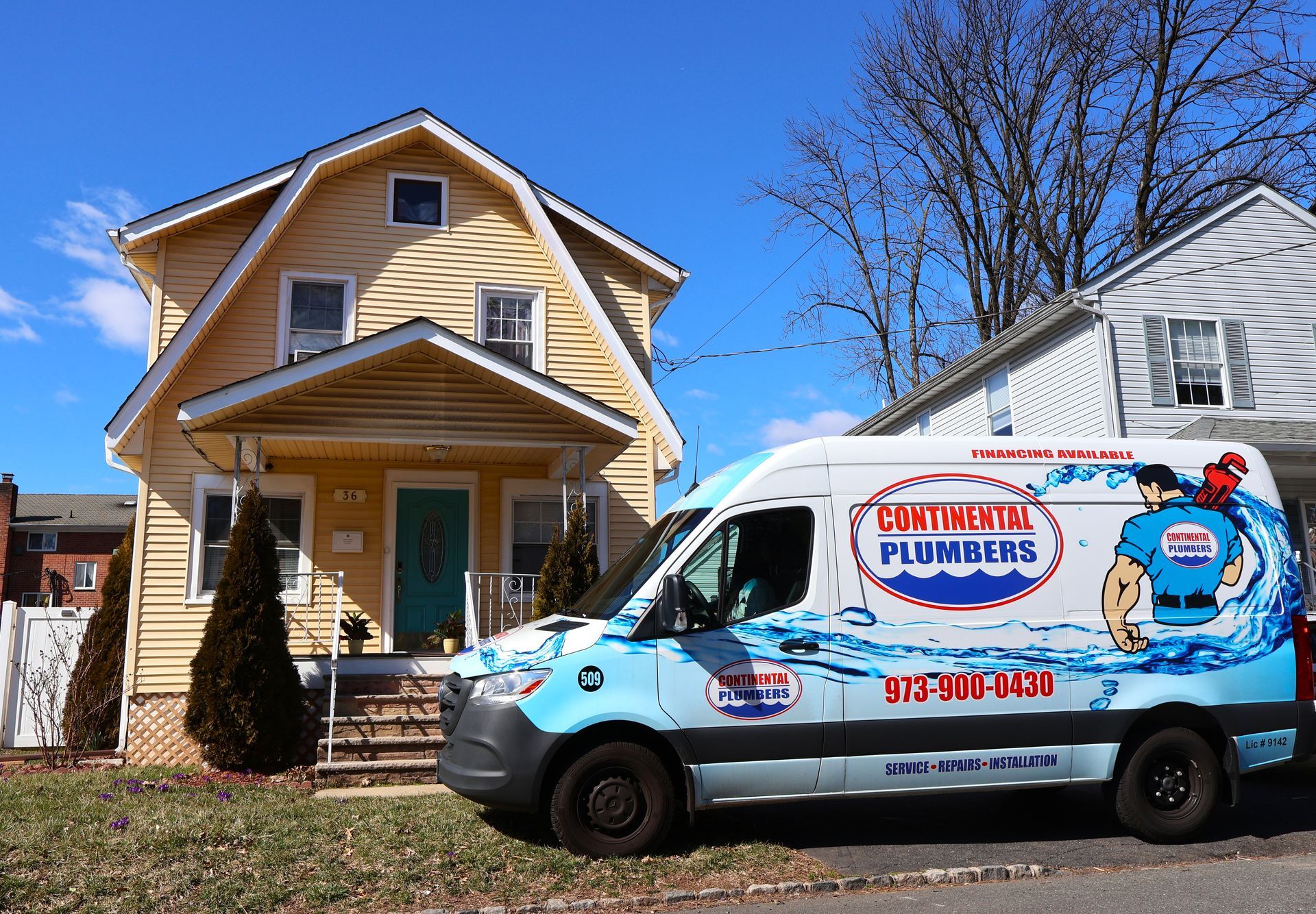 A plumbing van is parked in front of a house