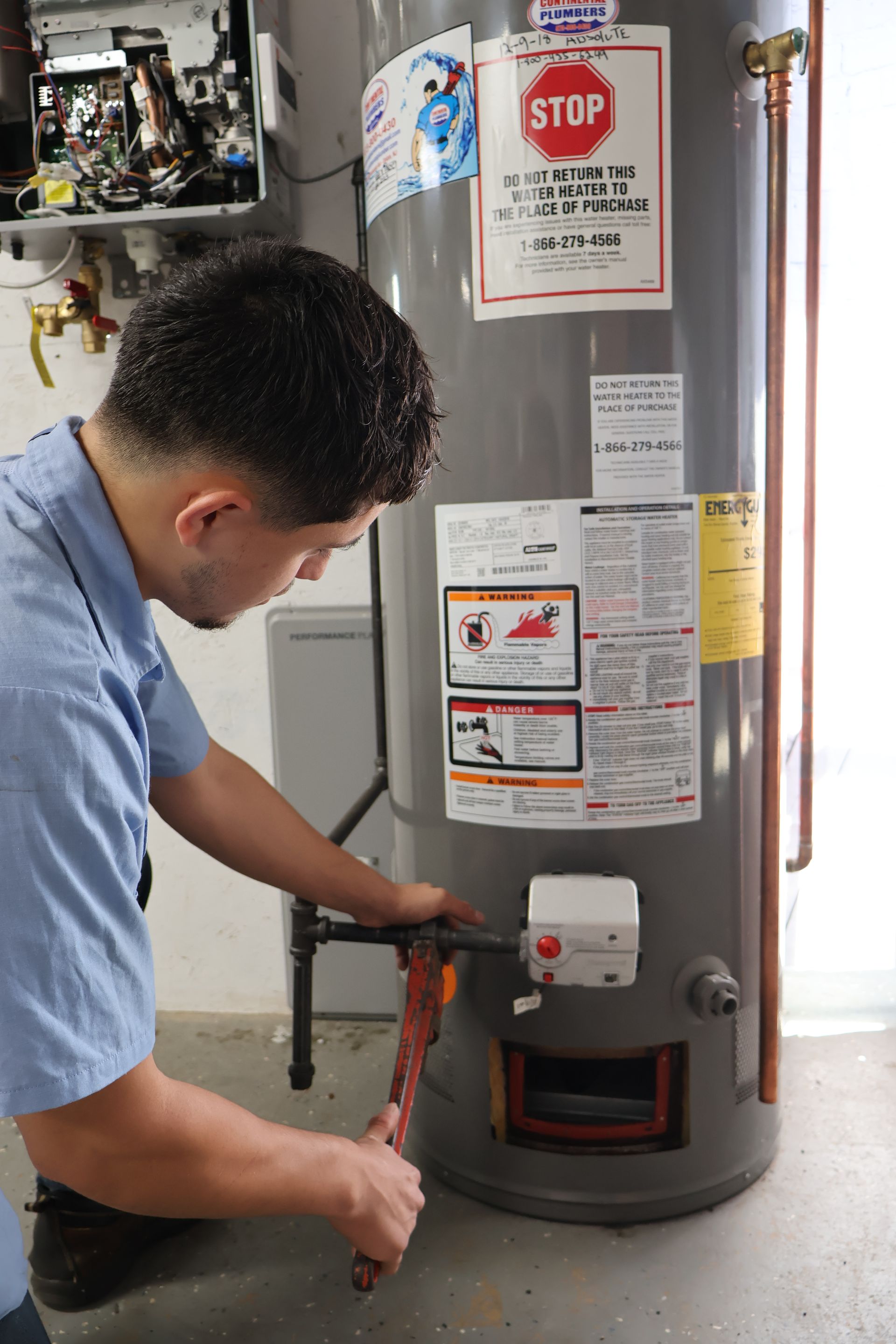 A man is working on a water heater with a stop sign on it.