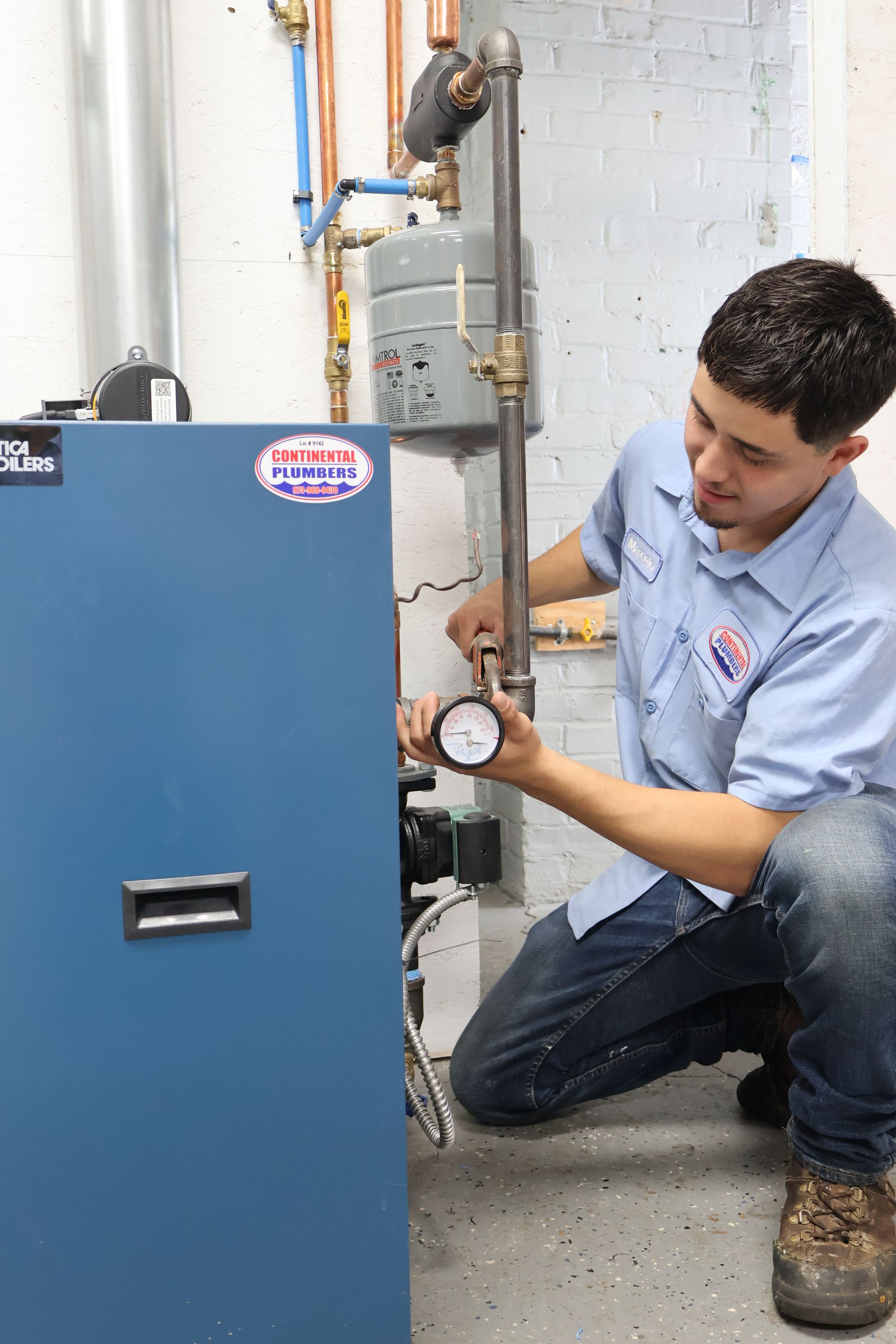 A man in a blue shirt is working on a boiler