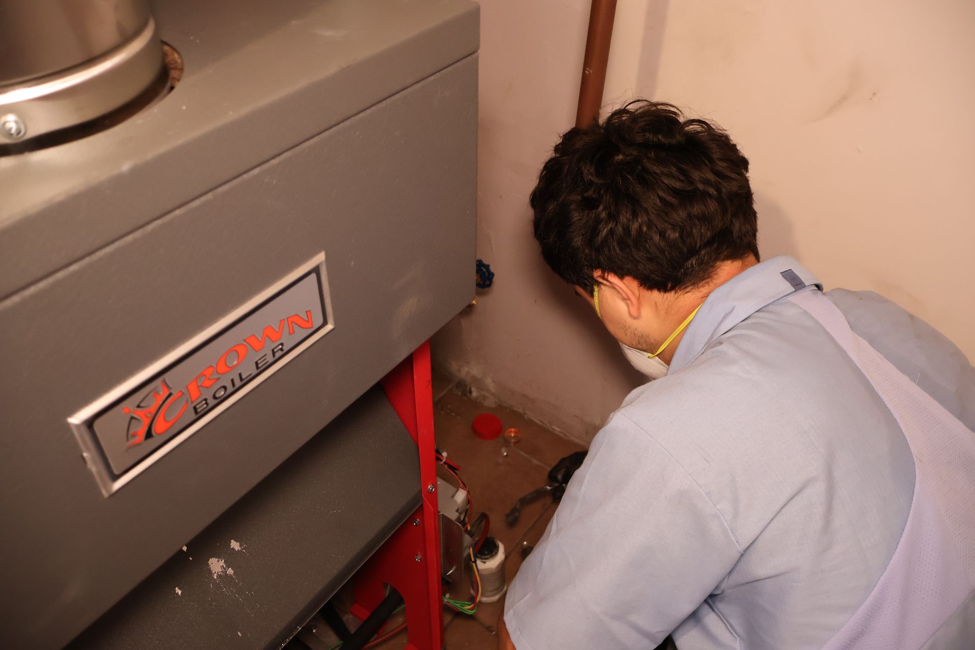 A man wearing a mask is working on a heating system A man wearing a mask is working on a heating system