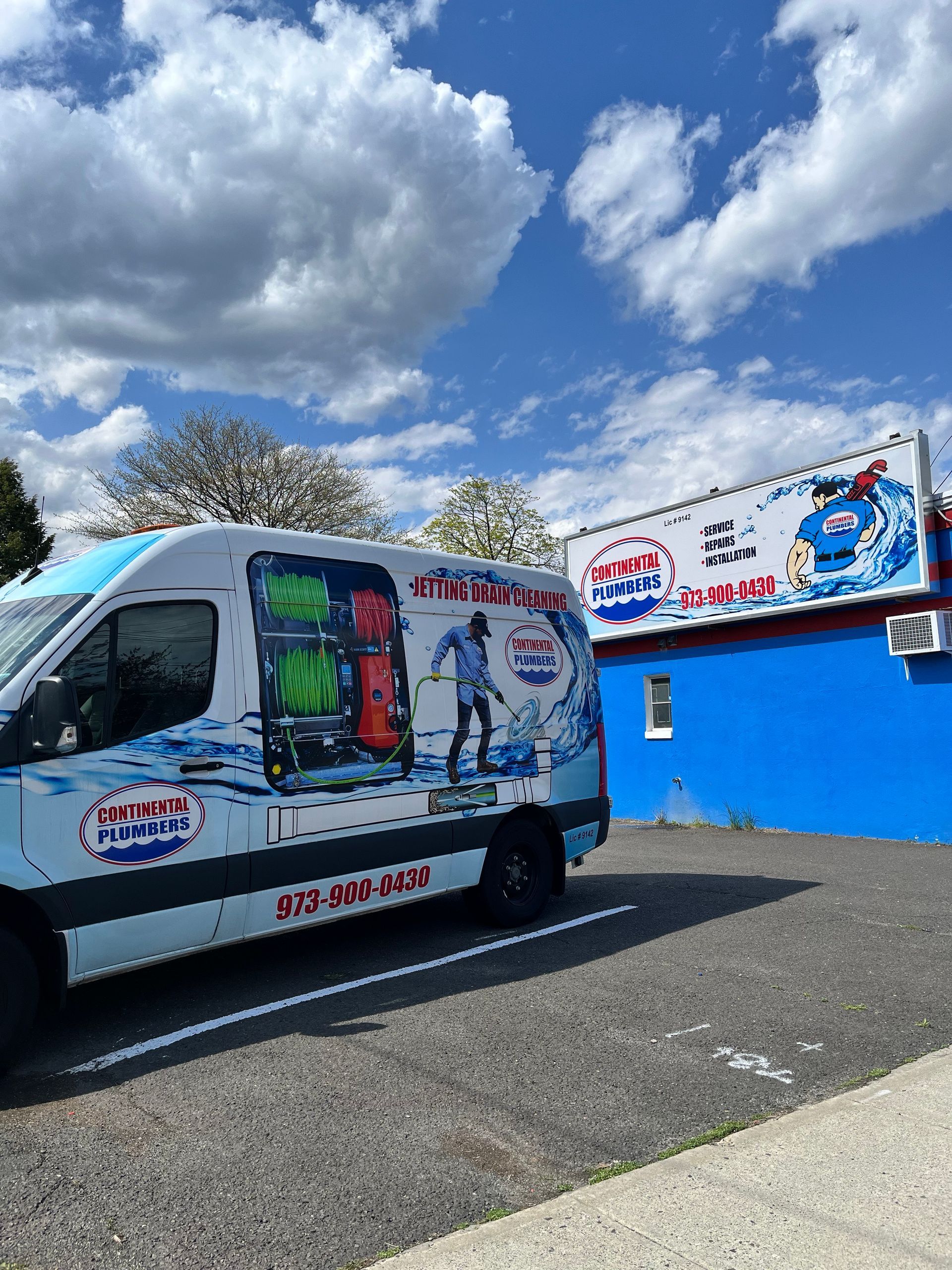 A white van is parked in front of a blue building.