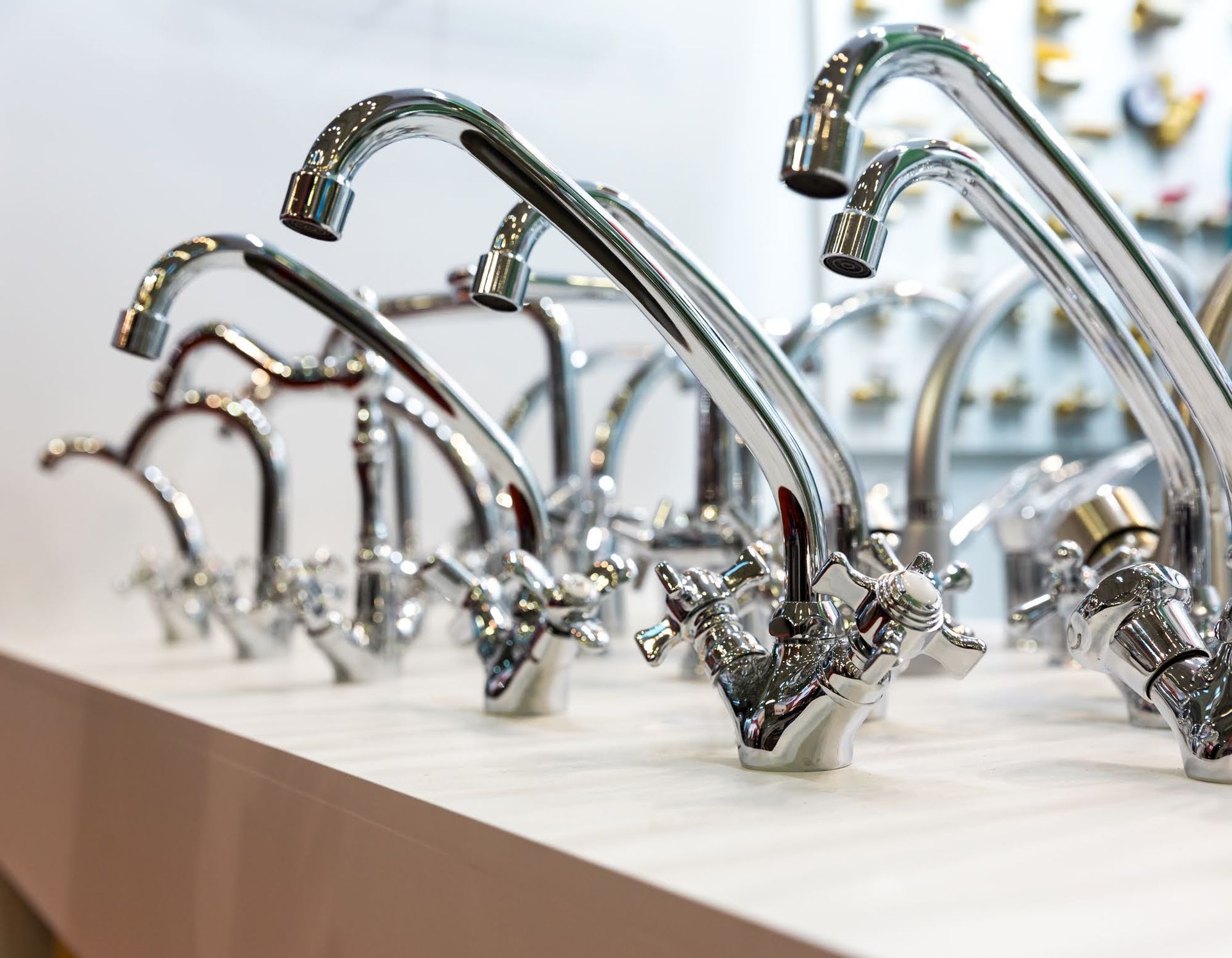A row of chrome faucets are lined up on a counter.