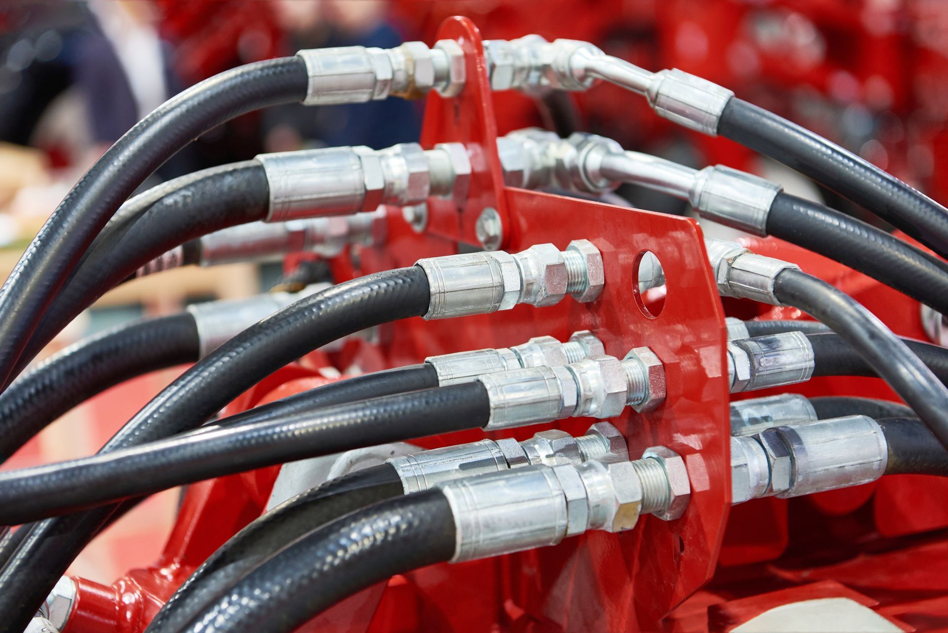 Black hydraulic hoses connected to a red metal plate, silver fittings visible.