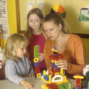 children and nursery nurse playing with construction toys