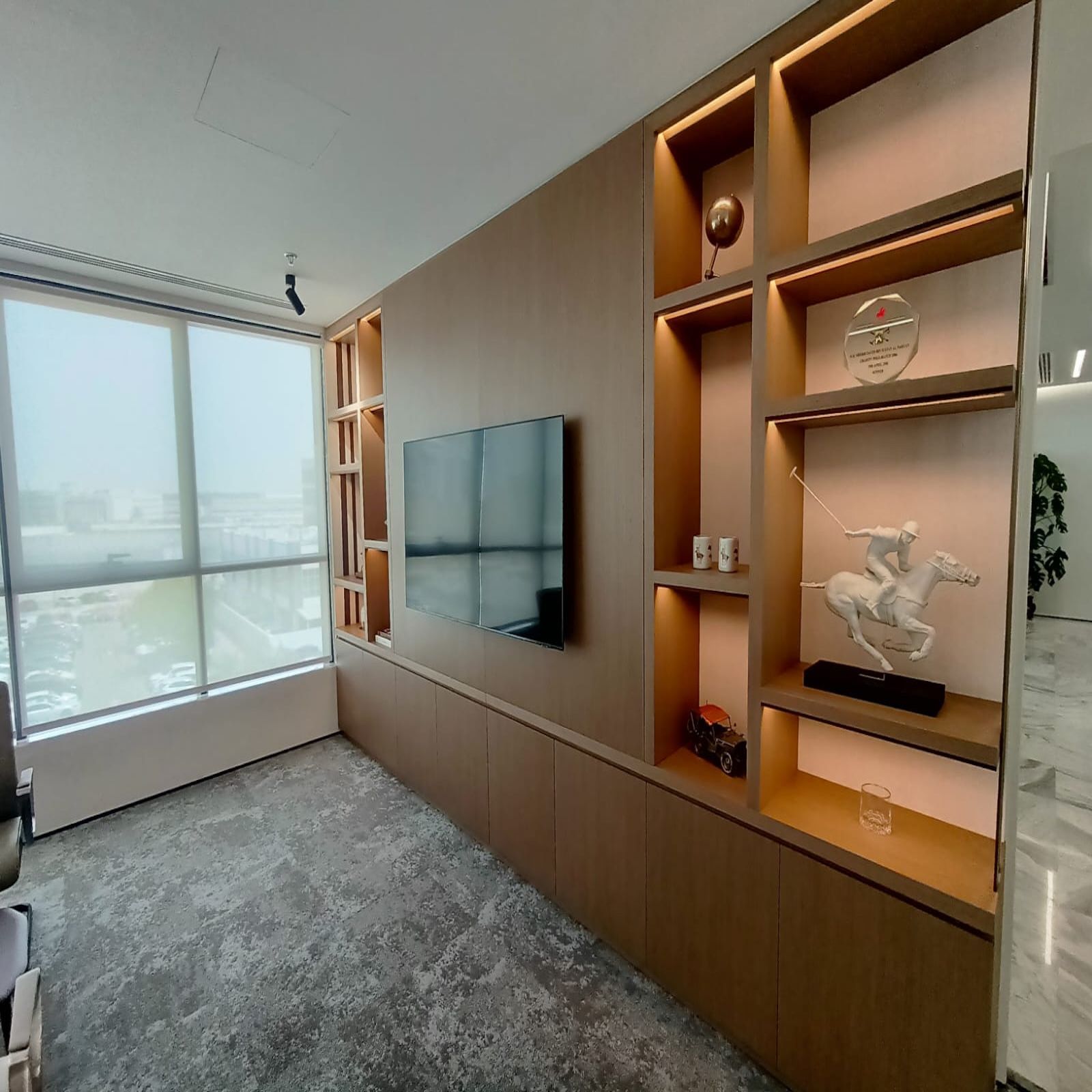 Custom wooden shelving with display lighting and TV wall mount