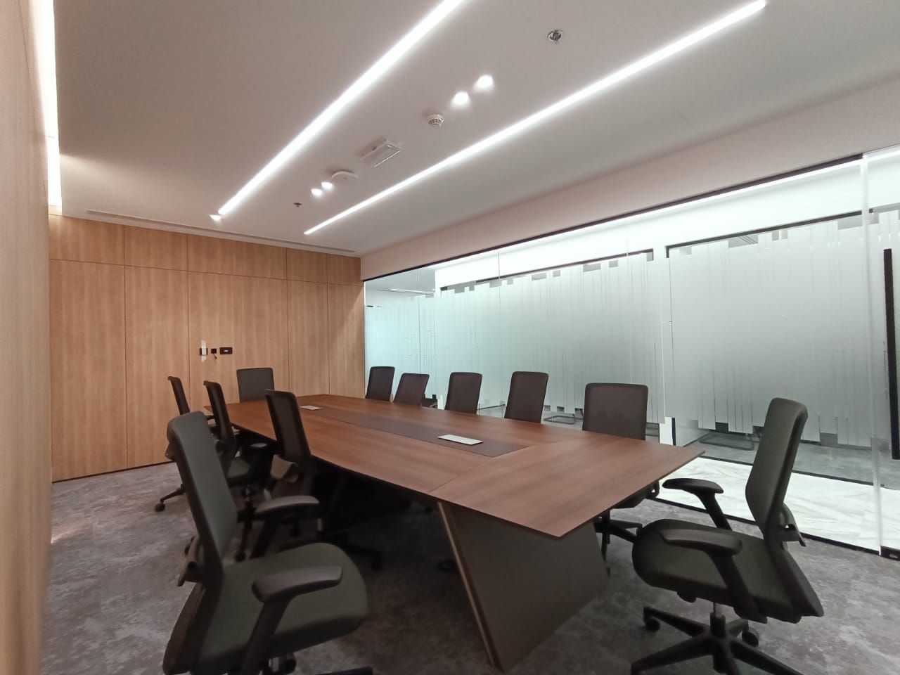 Modern boardroom with wooden walls and LED strip ceiling lights designed and executed by Concept Art Decor