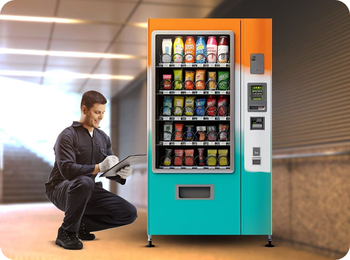 Man kneels, holding tablet, in front of a turquoise and orange vending machine in a tunnel.