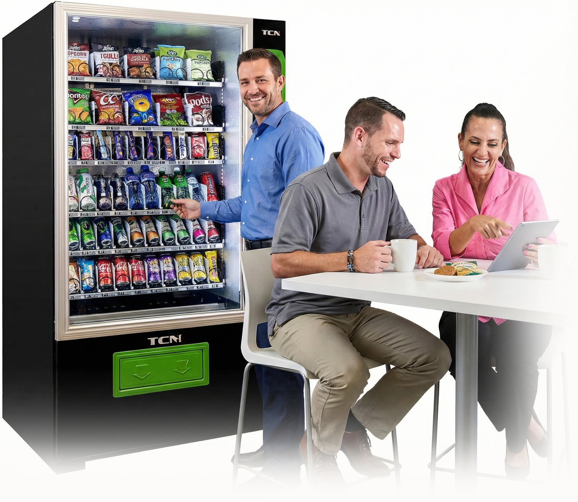 People near a vending machine; one person points at snacks, two sit at a table looking at tablet and smiling.