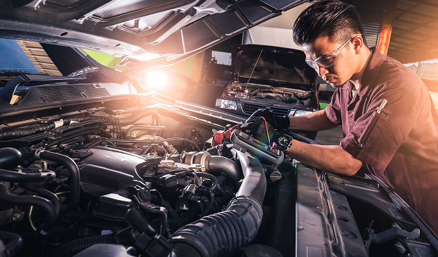 A man is working on the engine of a car in a garage.