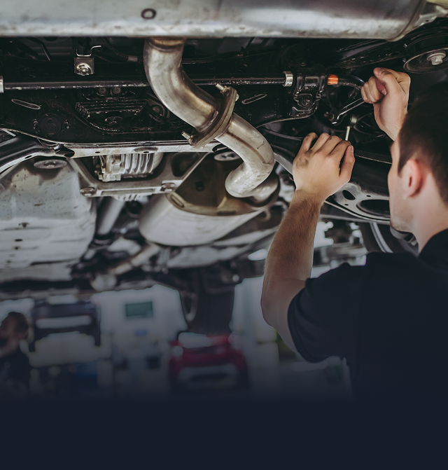 A man is working on the underside of a car
