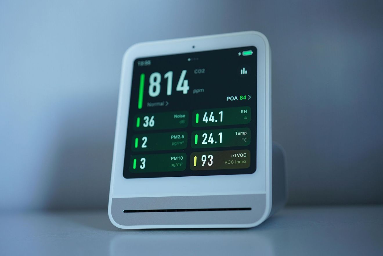 Air quality monitor displaying air quality readings in a brightly lit room.