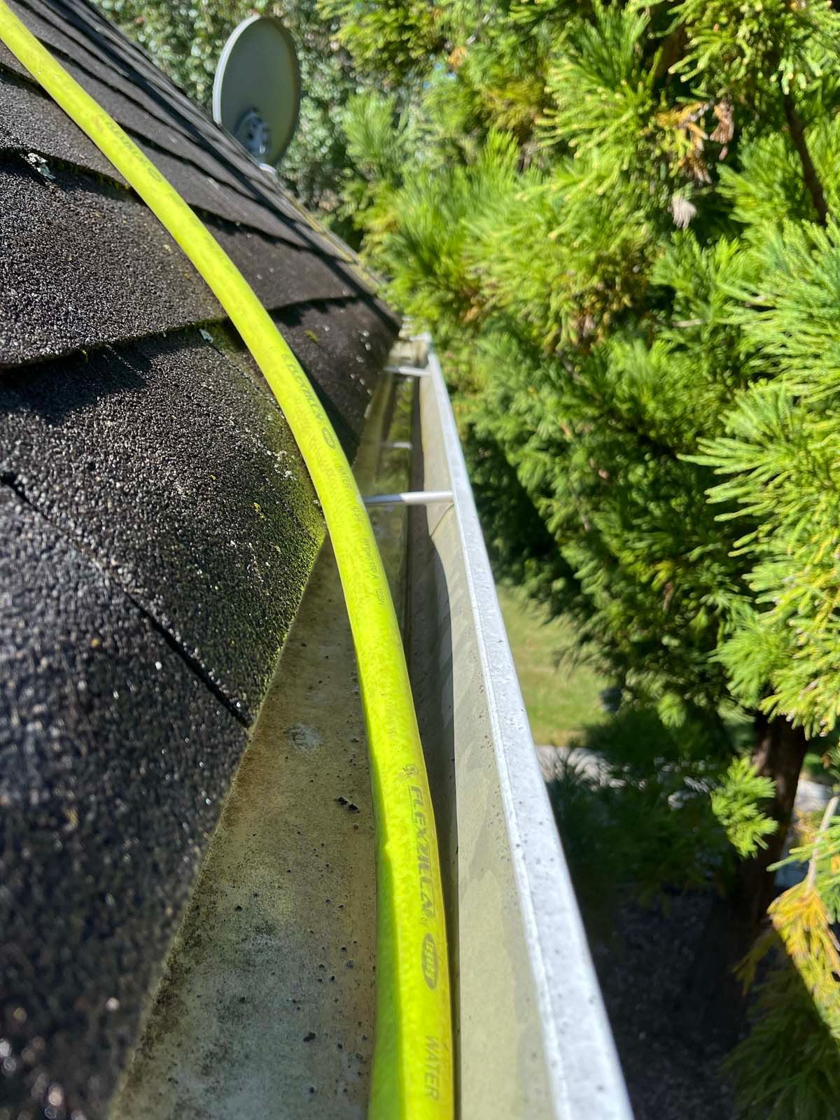 A yellow hose is attached to a gutter on a roof.