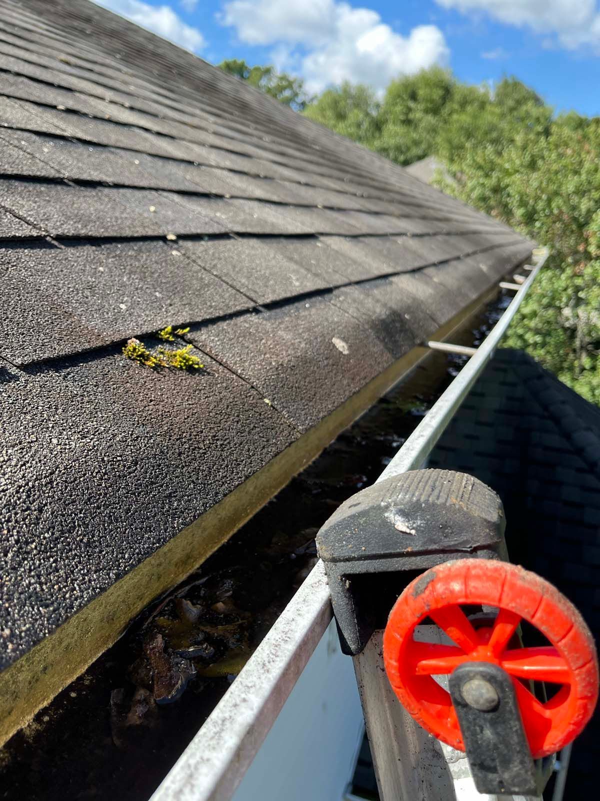 A close up of a gutter on a roof with a red wheel attached to it.