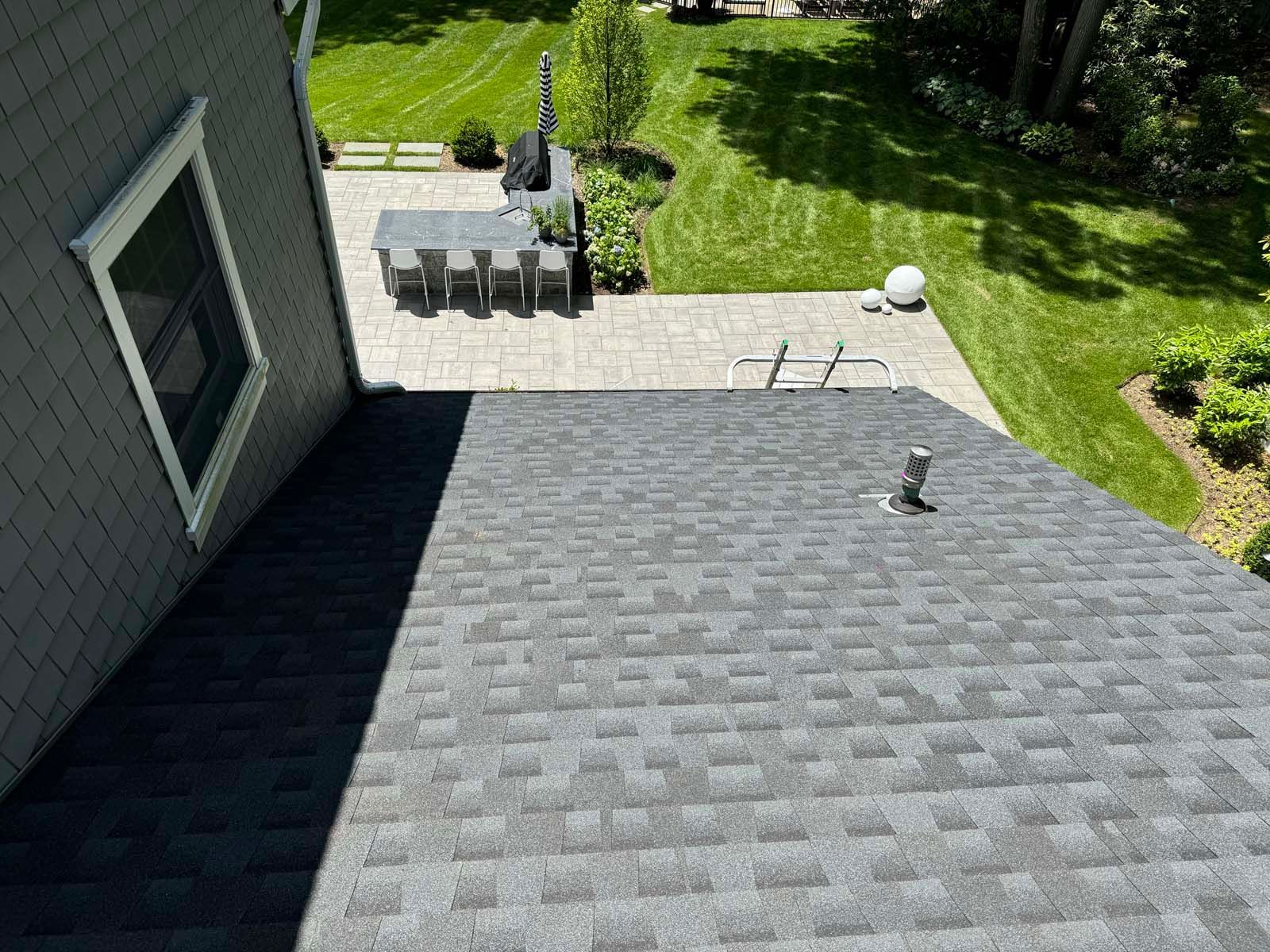 An aerial view of a roof with a patio in the background.