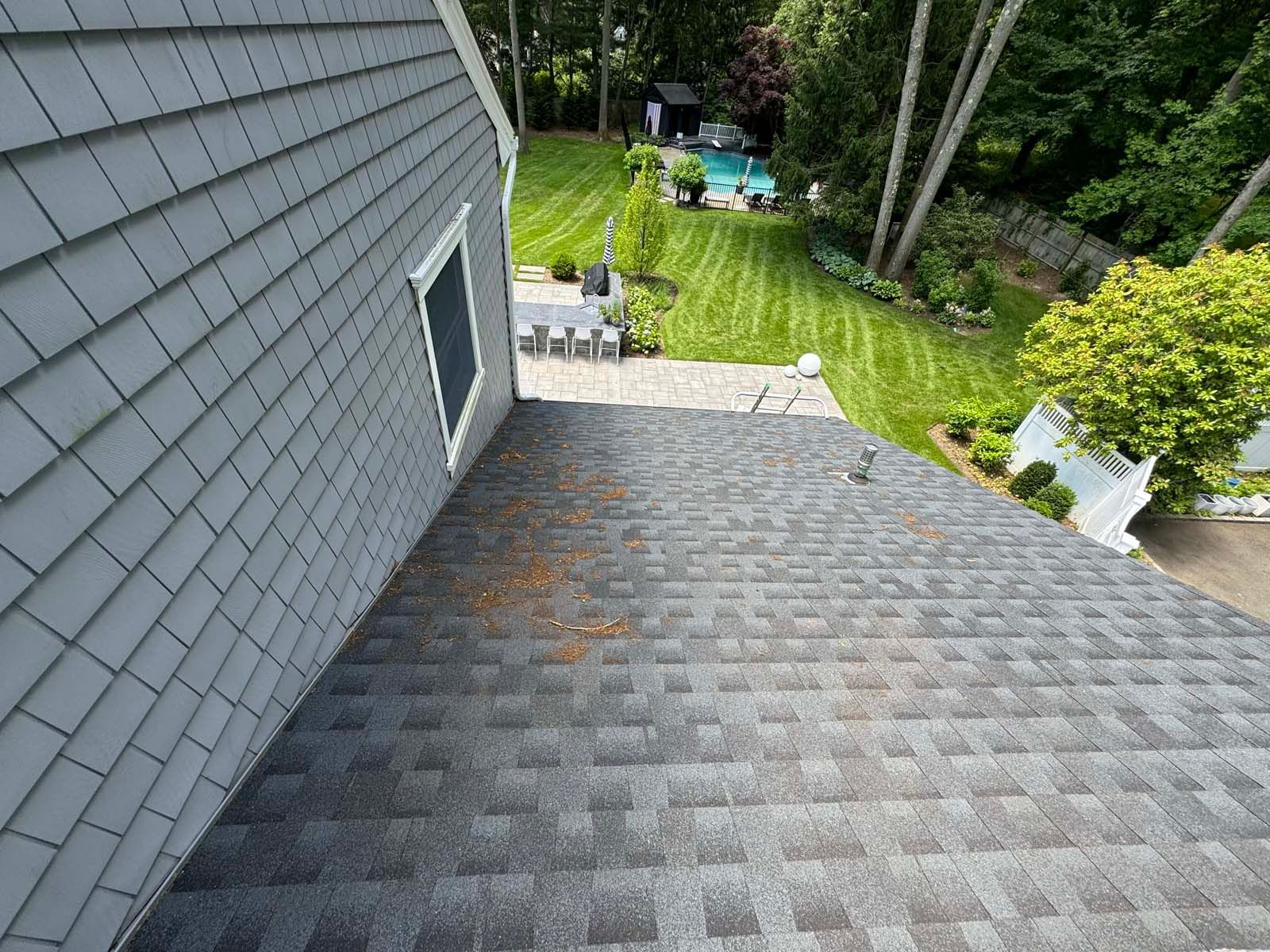 An aerial view of a roof of a house with a pool in the background.