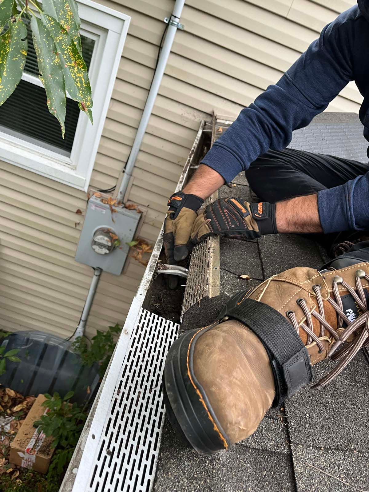 A man is fixing a gutter on the roof of a house.