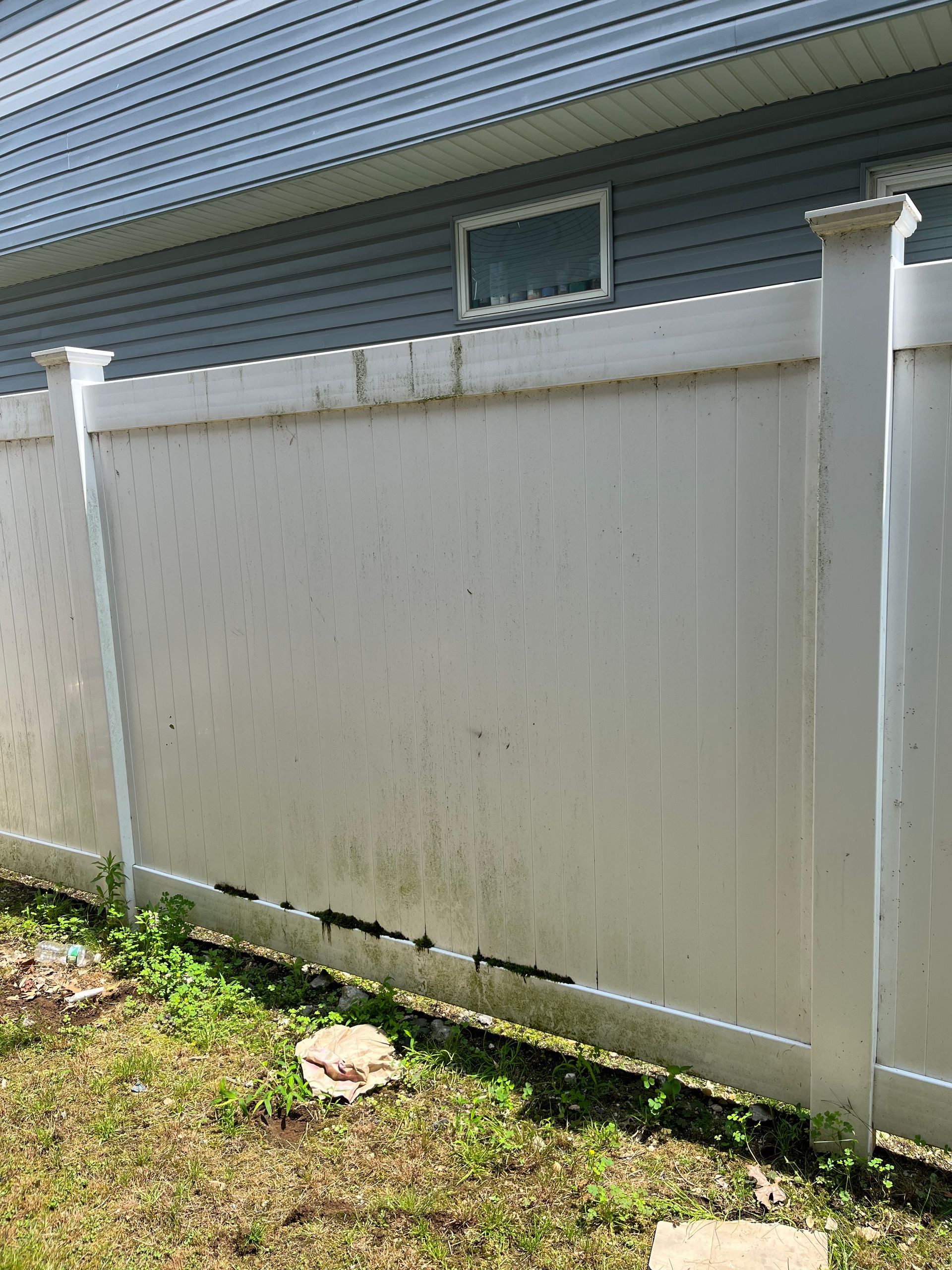 A white vinyl fence is sitting in front of a house.