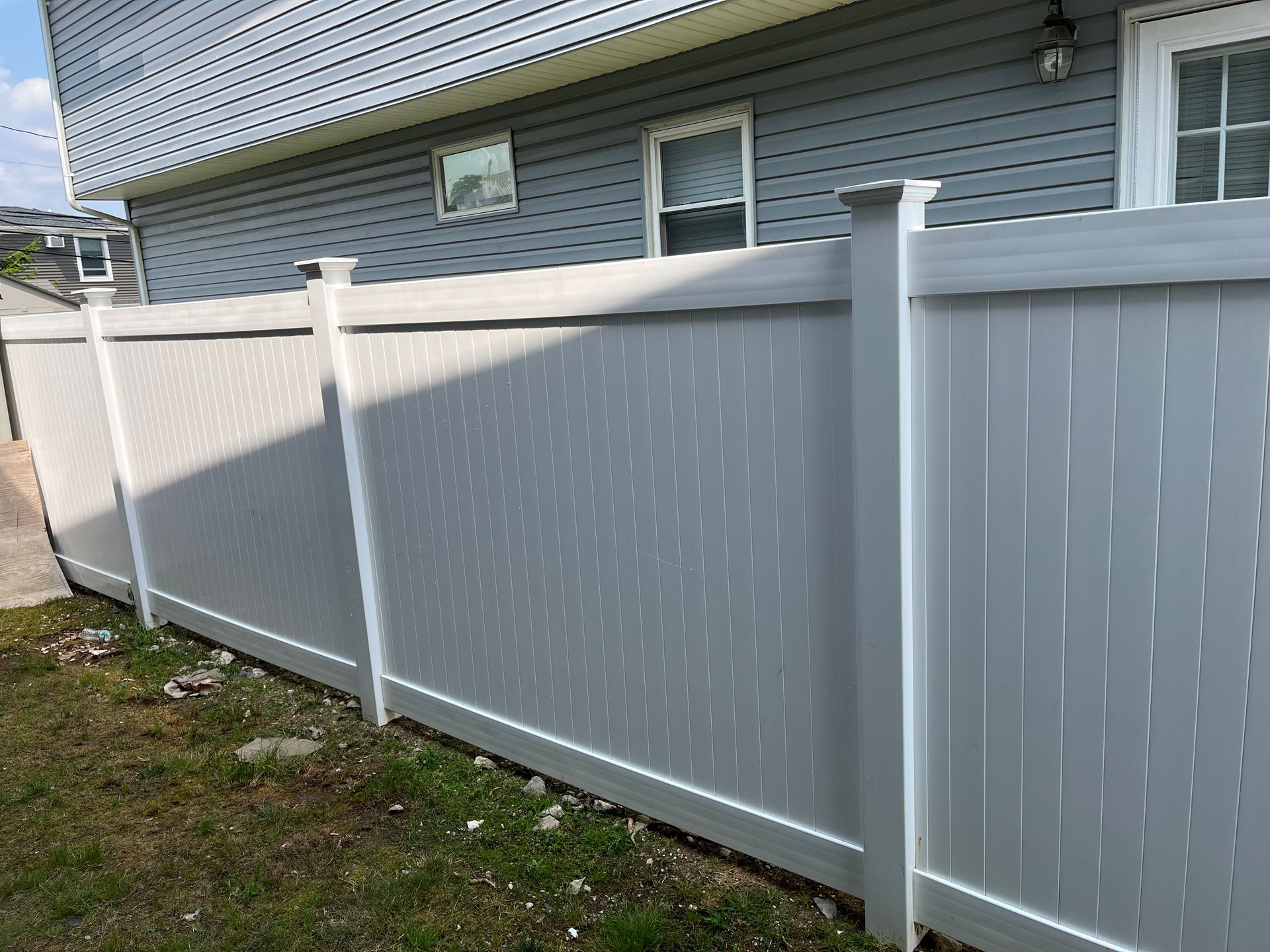A white fence is sitting in front of a house.