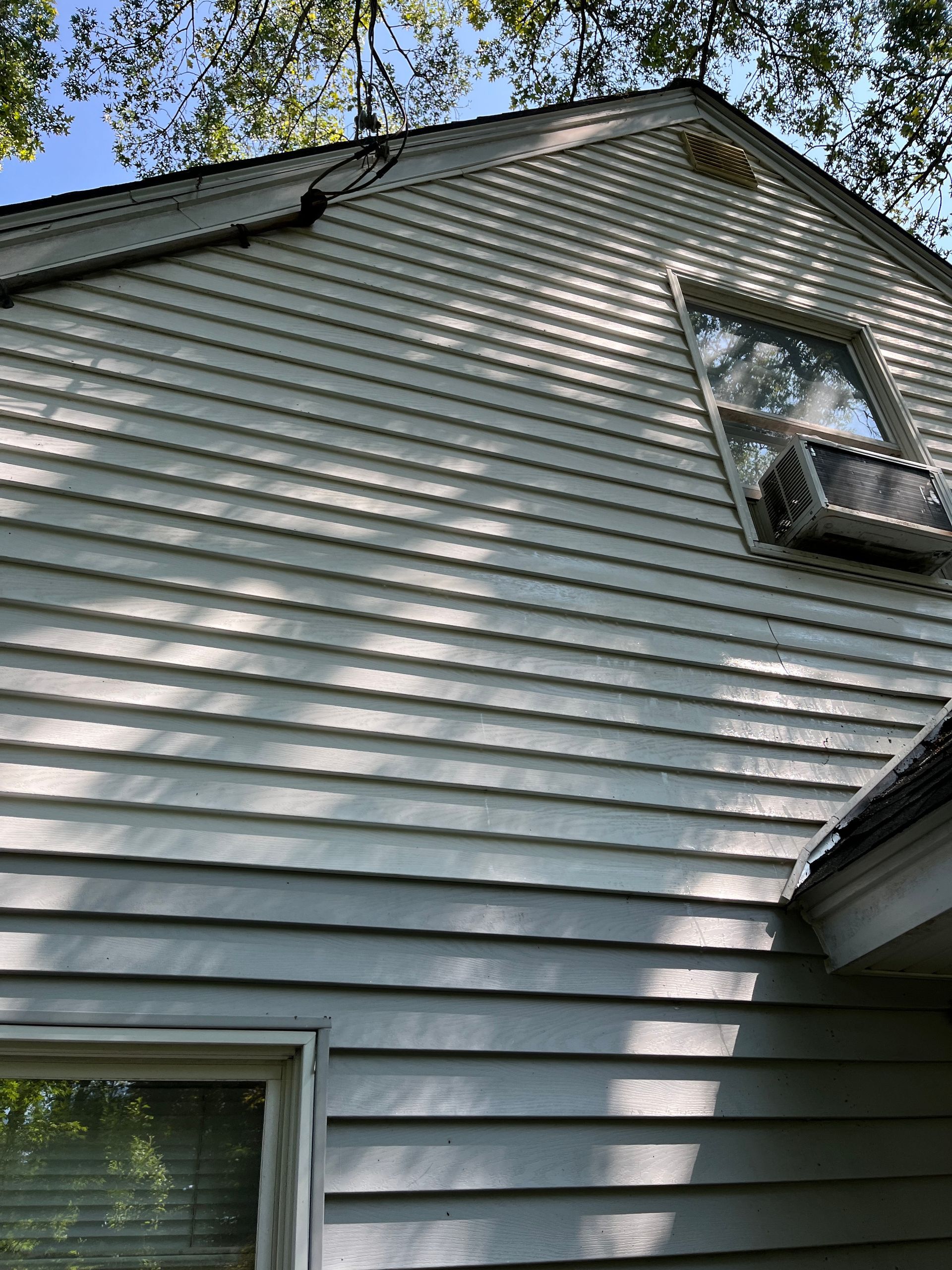 A white house with a window and air conditioner on the roof.