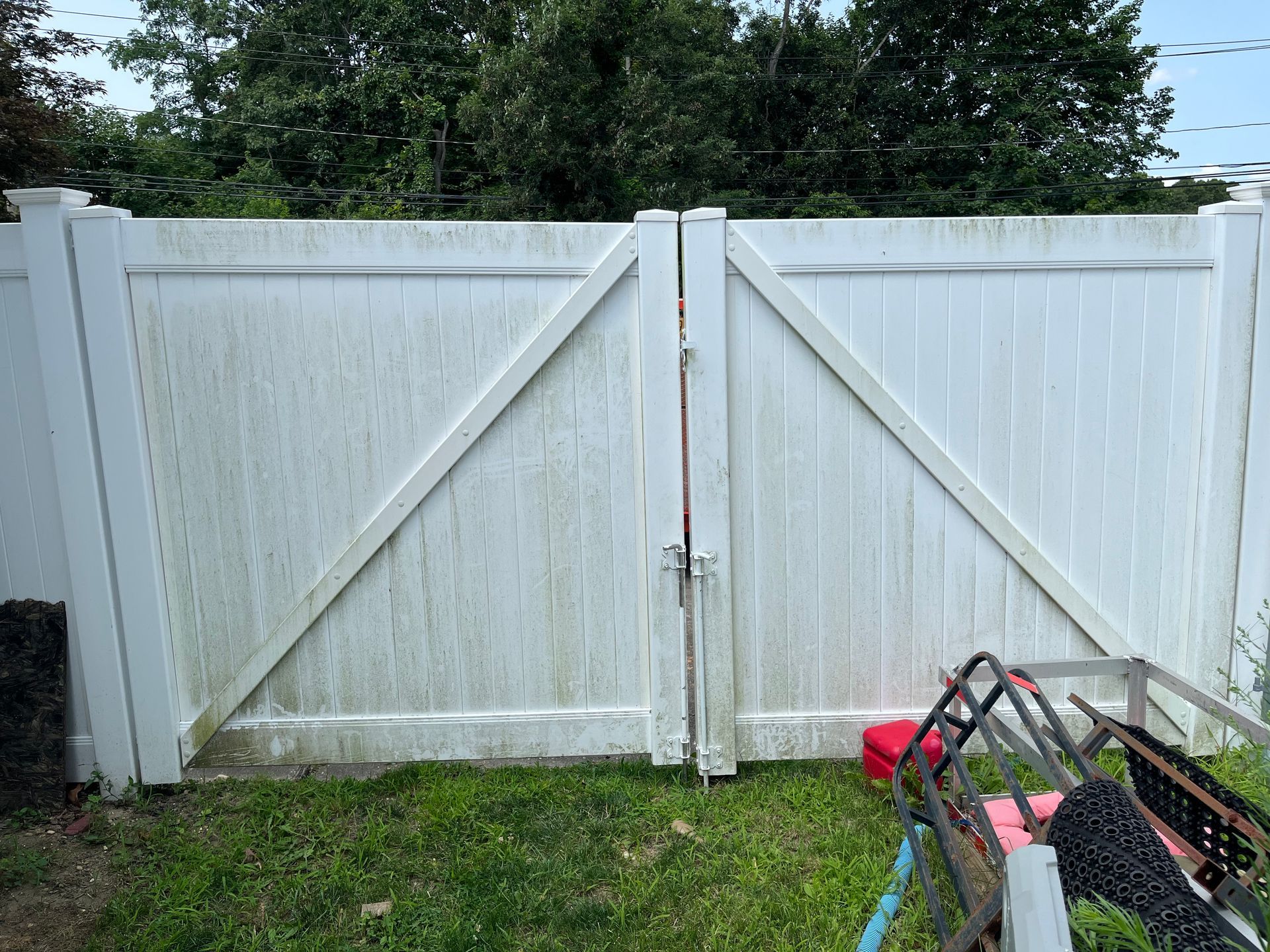 A white fence with a gate is sitting in the grass.