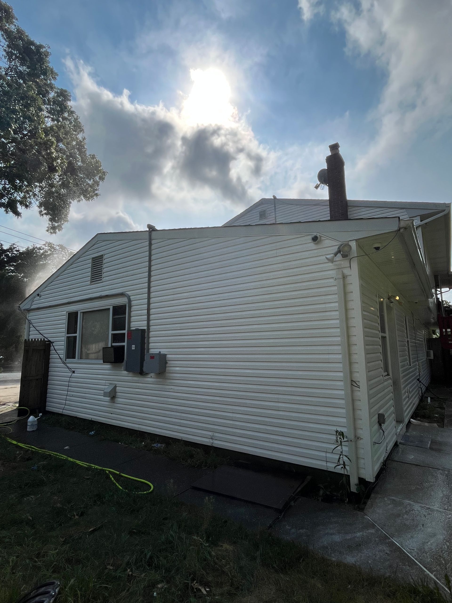 A man is cleaning the roof of a house with a pressure washer.