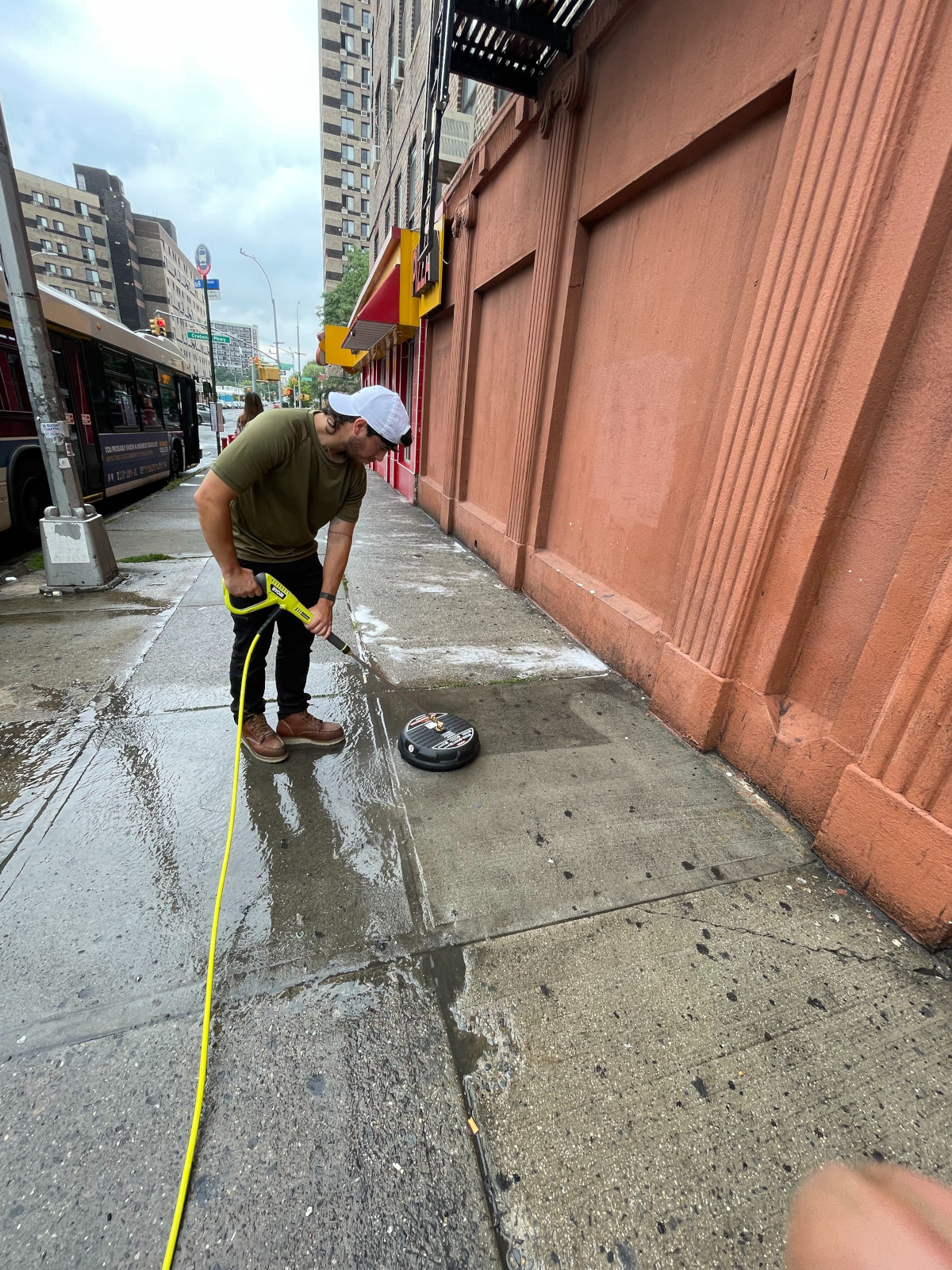 A man is cleaning the sidewalk with a hose.