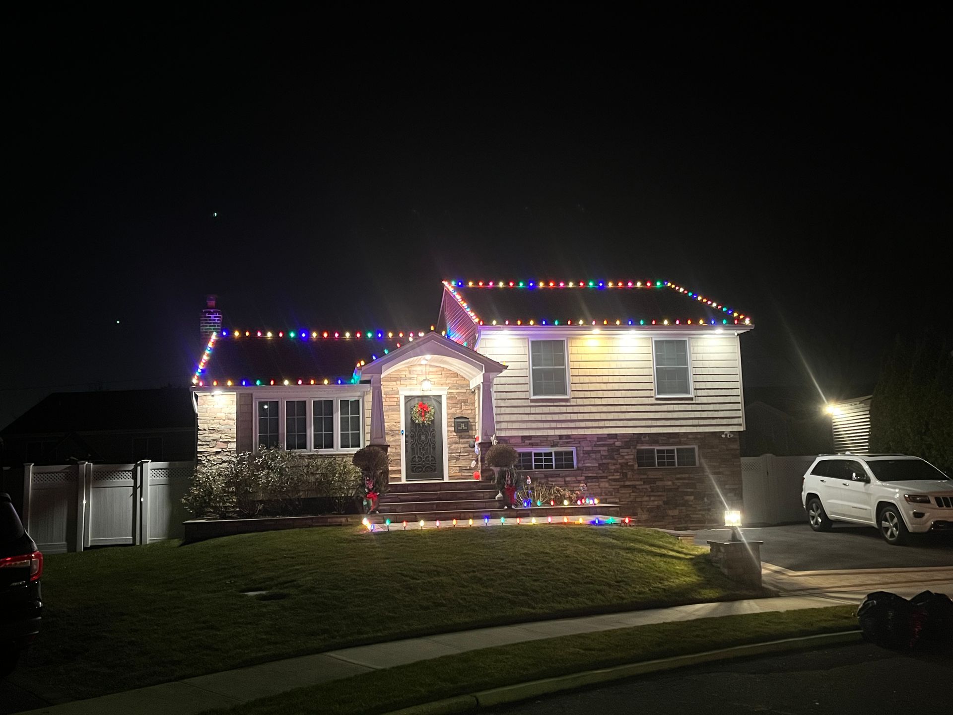 A house with christmas lights on it is lit up at night.