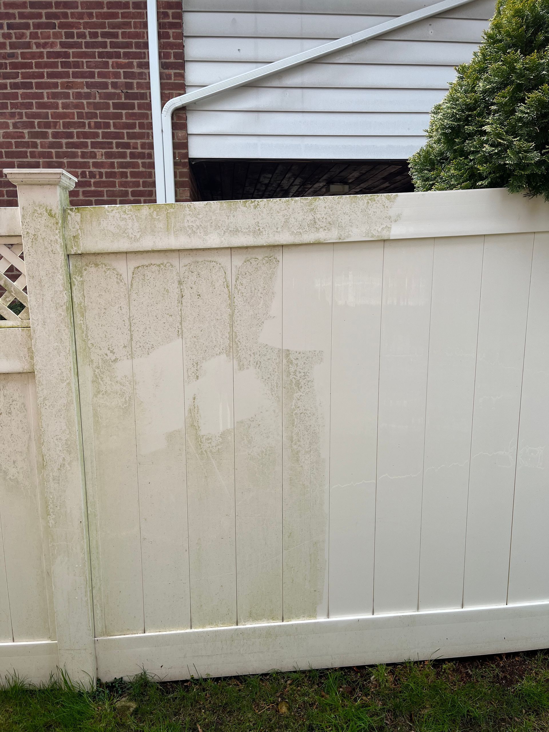 A white fence is sitting in front of a brick building.