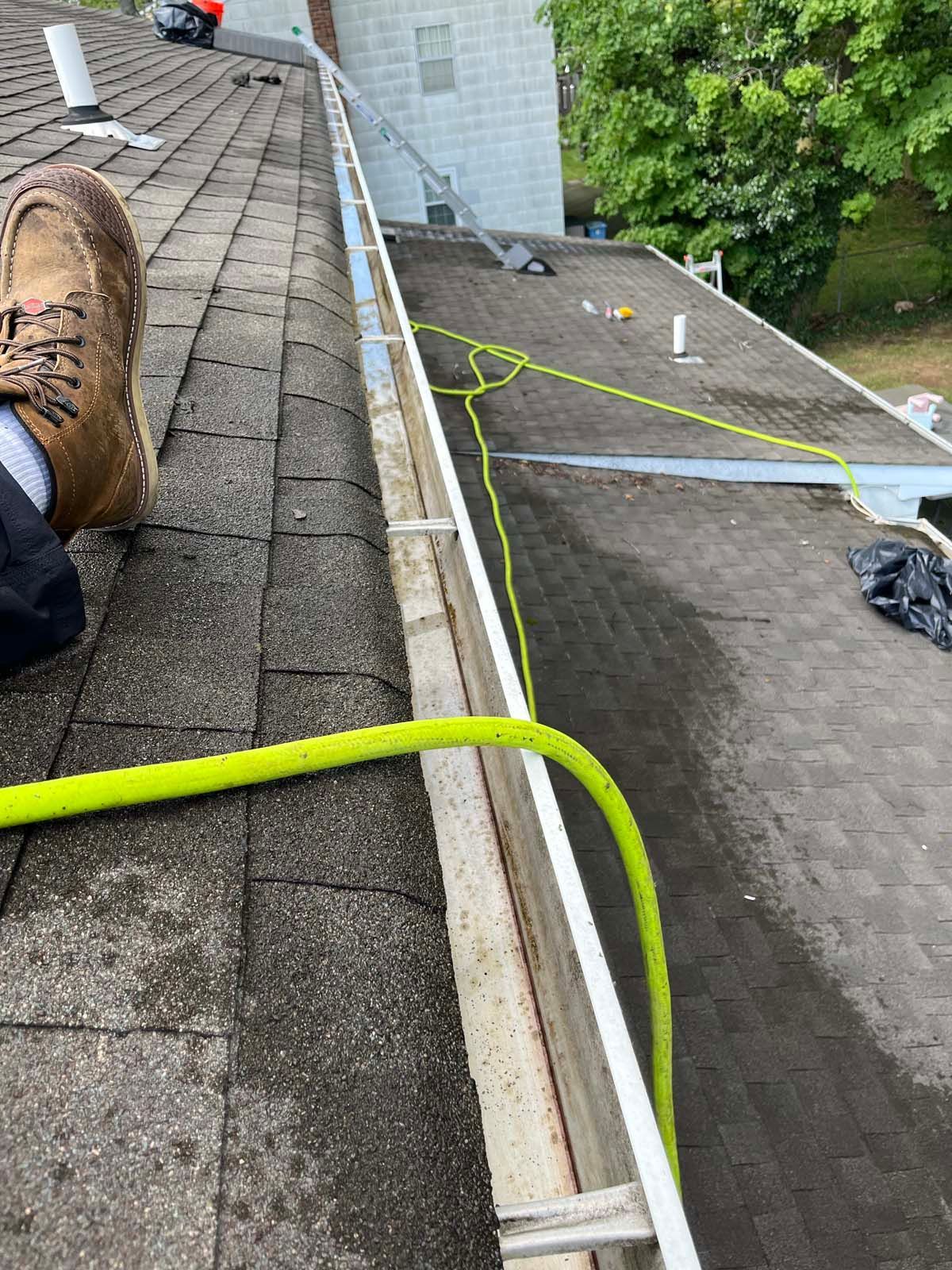 A person is standing on a roof with a hose attached to it.