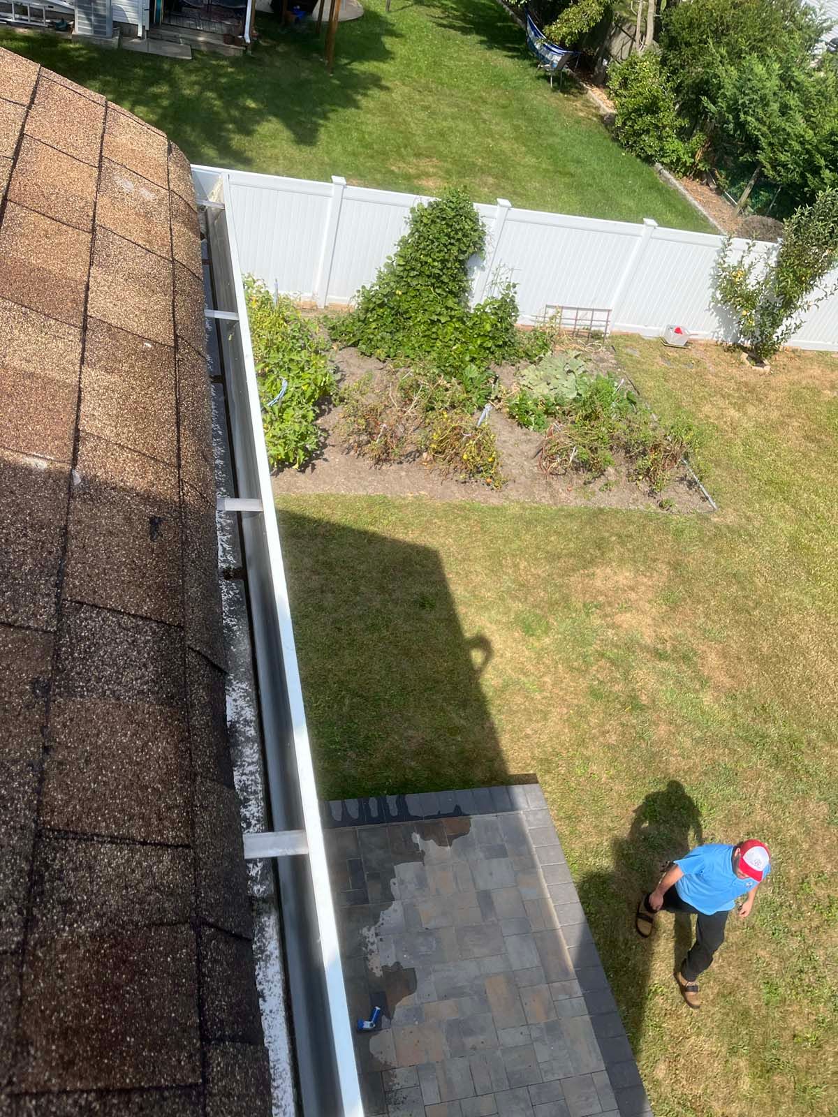 A man is standing on the roof of a house next to a gutter.