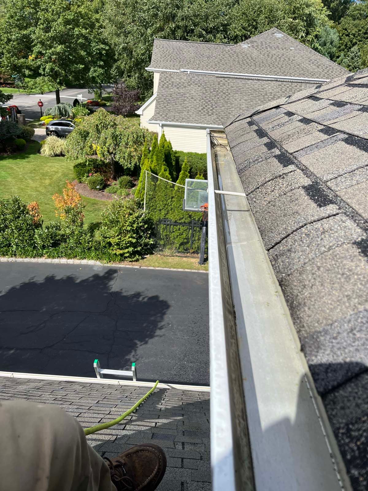 A person is cleaning a gutter on the roof of a house.